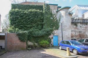 a ivy covered building with a car parked next to it at Monumental independent Studio, City Centre Dordrecht in Dordrecht