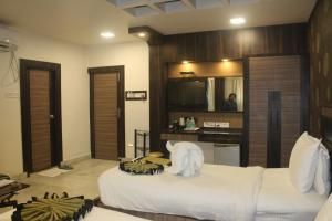 Schlafzimmer mit einem Bett mit weißer Bettwäsche und einem Spiegel in der Unterkunft Continental Lodge & Continental Residency in Māldah