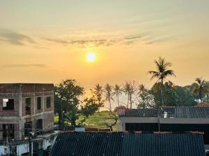 einen Sonnenuntergang über einer Stadt mit Gebäuden und Palmen in der Unterkunft Villa Yoshan in Ambalangoda