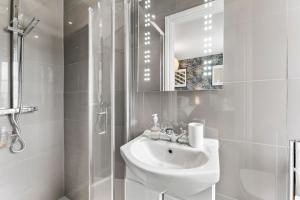 La salle de bains blanche est pourvue d'un lavabo et d'une douche. dans l'établissement The Stunning Gems of Central Canterbury -Sleeps 14!, à Kent