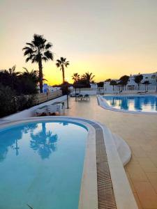 a large swimming pool with a sunset in the background at Casa Chus, cerca de la playa in Los Pocillos