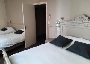 una camera con due letti e una porta di accesso ad una stanza di Hôtel de France a Tolosa