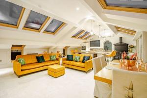 a living room with yellow furniture and a kitchen at Skyfall in Prestbury