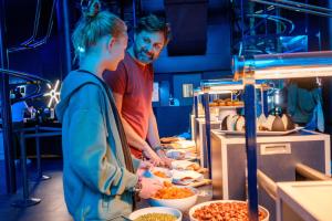 a man and a woman standing in a kitchen preparing food at Hôtel Station Cosmos in Chasseneuil-du-Poitou +10 photos