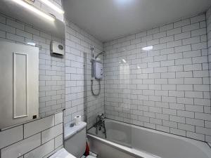 un bagno piastrellato bianco con vasca e servizi igienici di Riverside South Dublin City 2 bedroom a Dublino