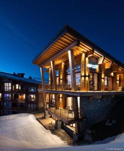 a large building with a deck in the snow at Résidence Arpoza - Chalets pour 15 Personnes 094 in Arc 1800