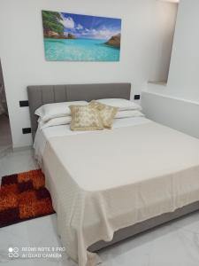 uma cama com lençóis brancos e almofadas num quarto em MEDUSA house em Taormina