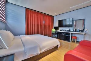 a bedroom with a large white bed and a red curtain at Hermes Hotel in Busan