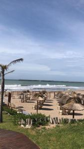 una playa con mesas y sombrillas de paja y el océano en Quequen - Casa Las Olas en Quequén