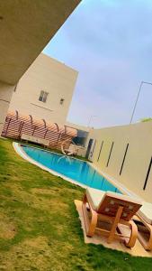 una piscina con 2 sillas y un banco junto a un edificio en كمباوند السليمانية en Riad