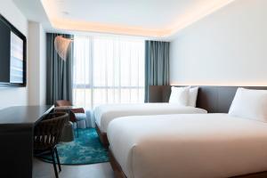 a hotel room with two beds and a desk at Labtwentytwo Barcelona, a Tribute Portfolio Hotel by Marriott in Barcelona