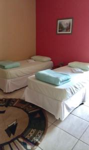 2 letti in una camera con parete rossa di Espaço Verona - Quarto duplo 2 camas de solteiro a Fazenda Rio Grande