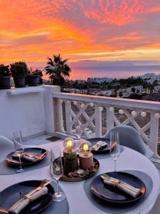 een tafel met borden en kaarsen op een balkon met een zonsondergang bij Sunshine Escape with ocean view in Adeje