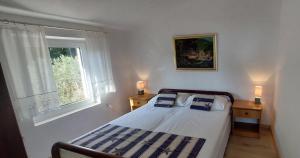 Schlafzimmer mit einem Bett und einem Fenster in der Unterkunft Apartments Basina in Vrbanj