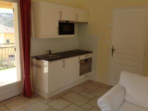uma cozinha com armários brancos, um lavatório e uma janela em Villa Fleury Appartement em Montbrun-les-Bains