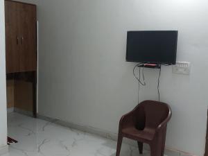 a room with a chair and a television on a wall at Hotel Kadamb, Palwal in Palwal