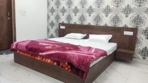 a bedroom with a bed with a purple blanket on it at Hotel Kadamb, Palwal in Palwal