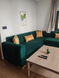a green couch in a living room with a coffee table at Appartement en m'diq centre ville près de la plage in M'diq