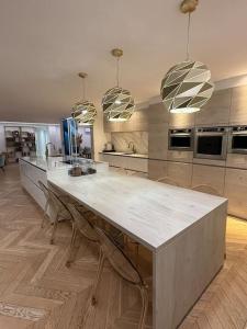 a kitchen with a large white counter and chairs at Villa de luxe JO 2024 in Saint-Brice-sous-Forêt