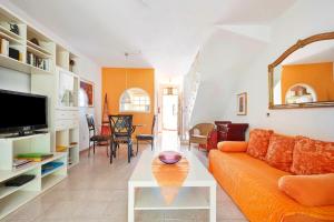 a living room with an orange couch and a table at Very well maintained house in Chayofa, the sunny south of Tenerife in Chayofa