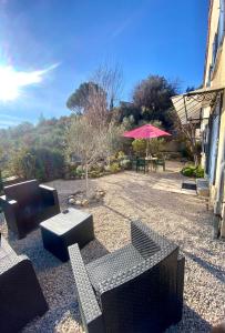 eine Terrasse mit Sofas und einem Tisch mit einem Sonnenschirm in der Unterkunft La rocaille du château in Gréoux-les-Bains