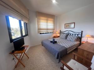 een slaapkamer met een bed, een bureau en een televisie bij Alquilaencanarias Duplex Playa del Médano in El Médano