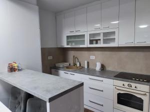 a kitchen with white cabinets and a counter top at Novak apartman in Subotica +1 photo