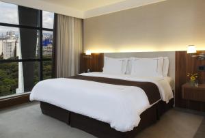 a large bed in a hotel room with a large window at Tivoli Mofarrej São Paulo in São Paulo