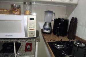 a kitchen counter with a microwave and a stove at Eletric Car Flat in Teófilo Otoni