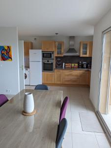 a kitchen with a wooden table with chairs and a kitchen with white appliances at Les Terrasses De Vignola in Porto-Vecchio