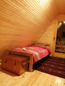 um quarto com uma cama num quarto de madeira em Taćina i Dokina kolibica em Arandjelovac