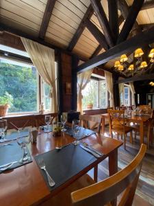 una sala da pranzo con tavoli e sedie in legno e finestre di The Patagonian Lodge a Coihaique