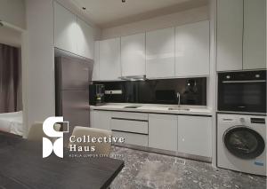 a kitchen with white cabinets and a washer and dryer at Royce Residence Kuala Lumpur by Collective Haus in Kuala Lumpur