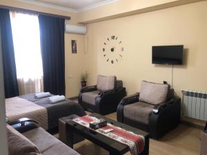 sala de estar con sofá y reloj en la pared en Уютная квартира в центре, en Ereván