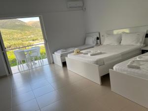 ein weißes Schlafzimmer mit 2 Betten und einem Balkon in der Unterkunft Villa Noel Borsh in Borsh