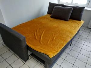 - un lit avec une couverture jaune au-dessus dans l'établissement Confortable appart 5 mins centre de valenciennes, à Anzin