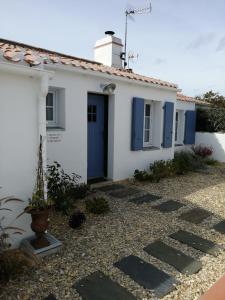 une maison blanche avec des portes bleues et une cour dans l'établissement nataliledeco bed and breakfeast, à La Guérinière