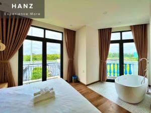 a bedroom with a bath tub and a large window at HANZ Sofia Hotel Grand World in Phu Quoc