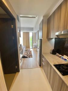 a kitchen with a counter and a living room at Skylounge Balikpapan by Wika Realty in Sepinggang-besar