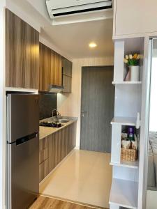 a kitchen with a stainless steel refrigerator and wooden cabinets at Skylounge Balikpapan by Wika Realty in Sepinggang-besar