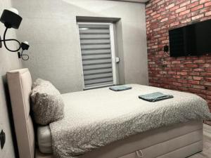 1 dormitorio con cama y pared de ladrillo en Raciborska Royal Apartment, en Gliwice