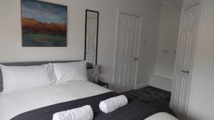 a bedroom with a white bed with a painting on the wall at Alexander Apartments Hebburn in Hebburn-on-Tyne