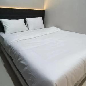a large white bed with white sheets and pillows at Zio Zildan Homestay in Sibengkok