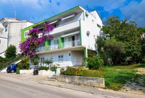 a white building with purple flowers on a street at Apartments Sonja in Tučepi