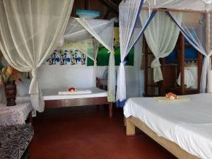 a bedroom with two beds with curtains and a table at Piscine bimoko in Nosy Be