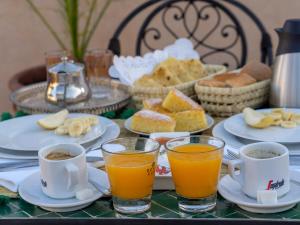 a table with plates of food and cups of orange juice at Riad Amalia in Marrakech