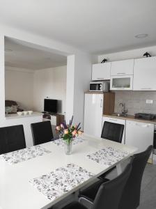 a dining room table with chairs and a vase of flowers at Zoran Vukusic Apartment in Kostrena