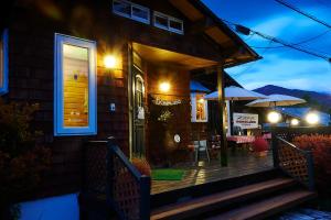 a house with a deck with tables and umbrellas at Lake village donaludo Pension in Kitashiobara