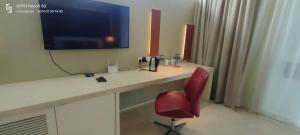 a desk with a red chair and a television on a wall at Port Dickson Leisure Water Villa in Port Dickson