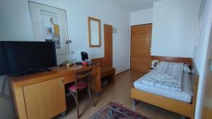 um pequeno quarto com uma secretária, uma cama e uma televisão em Pension Kappel em Ried im Innkreis